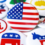 Collection of round American election campaign buttons featuring U.S. flags, stars, donkeys, elephants, and red, white, and blue political symbols