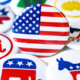Collection of round American election campaign buttons featuring U.S. flags, stars, donkeys, elephants, and red, white, and blue political symbols