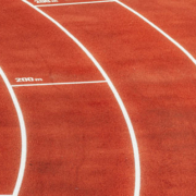 Athlete running along a curved section of a red running track during athletic training