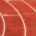 Athlete running along a curved section of a red running track during athletic training