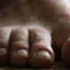 Front view of a single bare human foot resting on the ground, showing the big toe and four smaller toes