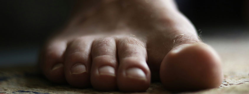 Bare-Human-Foot-Standing-With-Toes-Visible-From-Front Front view of a single bare human foot resting on the ground, showing the big toe and four smaller toes