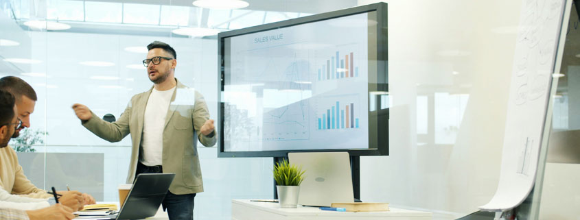 Business-Marketing-Presentation-Digital-Whiteboard-Team-Meeting Business professional presenting marketing and sales concepts on a digital whiteboard while colleagues listen during an office meeting