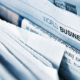 Multiple business newspapers arranged on a display stand, with one visible section labeled World Businesses B3