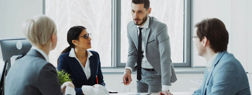 Businesswoman discussing reports with male and female colleagues seated around a table in a modern office