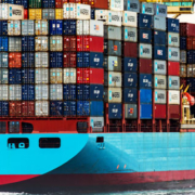 Large cargo ship loaded with stacked shipping containers traveling across the water