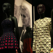 Christian Dior designer dresses displayed on mannequins at the Victoria and Albert Museum in London, featuring elegant red and coordinated haute couture outfits