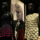 Christian Dior designer dresses displayed on mannequins at the Victoria and Albert Museum in London, featuring elegant red and coordinated haute couture outfits
