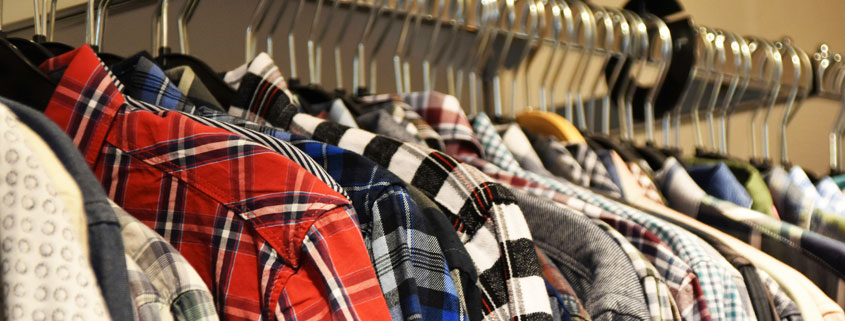 Colorful-Shirts-Hanging-on-Clothing-Rack-in-Fashion-Store Colorful shirts neatly arranged on hangers along a clothing rack, displaying a variety of colors and styles in a retail fashion setting