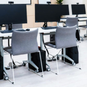 Room filled with multiple computer workstations equipped with webcams and chairs, arranged in a shared computing environment