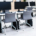Room filled with multiple computer workstations equipped with webcams and chairs, arranged in a shared computing environment