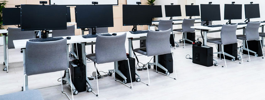 Computer-Workstations-With-Webcams-and-Chairs-in-Shared-Office Room filled with multiple computer workstations equipped with webcams and chairs, arranged in a shared computing environment