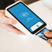 Customer inserting a payment card into a handheld card reader held by another person during a business transaction