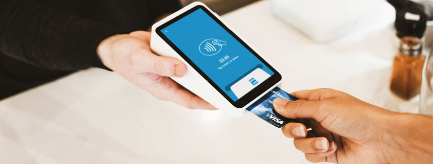 Customer inserting a payment card into a handheld card reader held by another person during a business transaction