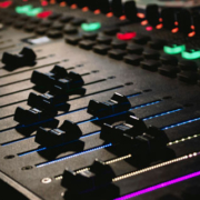 DJ mixing console with brightly illuminated buttons and sound controls in a dark party environment