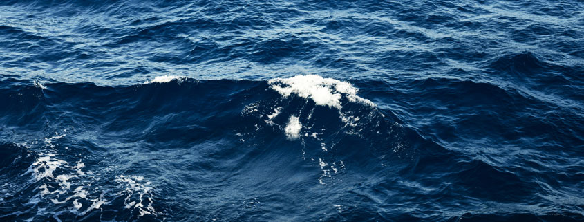 Deep blue ocean surface with powerful rolling waves and intense patterns of moving seawater