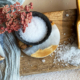 Assortment of salt crystals in different grain sizes, displayed in small dishes, metal trays, and a wooden scoop