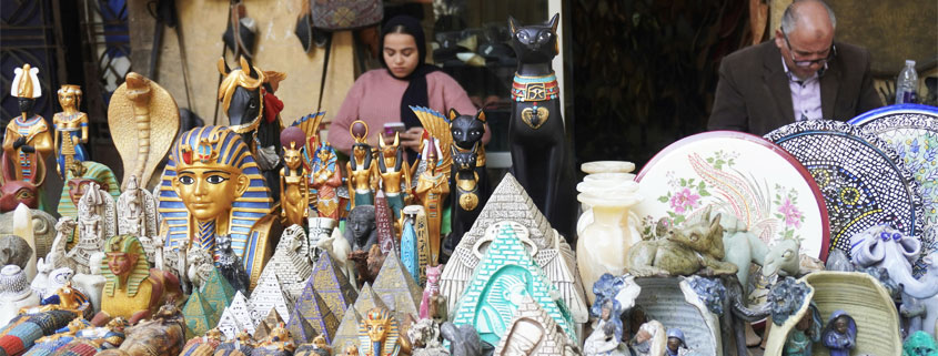 Egyptian-Souvenir-Shop-Display-With-Pyramids-and-Ancient-God-Figurines Egyptian souvenir shop displaying miniature pyramids, ancient Egyptian deity figurines, black cat statues, and decorative keepsakes