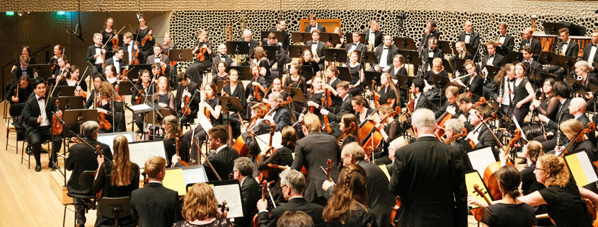 Musicians preparing for an orchestral performance before a large audience inside the Elbphilharmonie concert hall in Hamburg, Germany