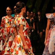 Group of glamorous fashion models walking along a runway in elegant outfits showcasing different clothing designs