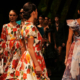 Group of glamorous fashion models walking along a runway in elegant outfits showcasing different clothing designs