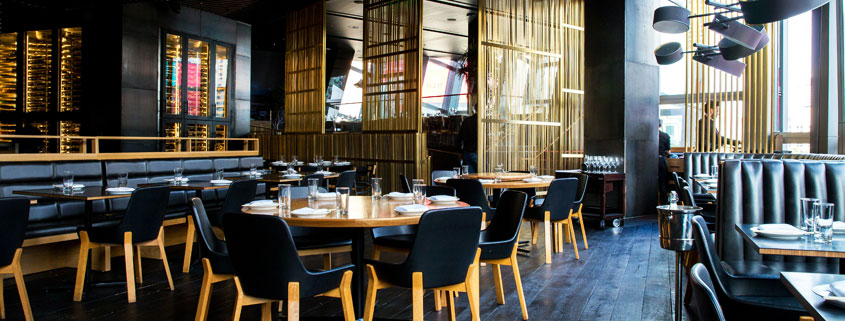 Elegant-Restaurant-Interior-With-Neatly-Arranged-Tables-and-Chairs Elegant restaurant interior with clean, neatly arranged tables and chairs and employees working in the background