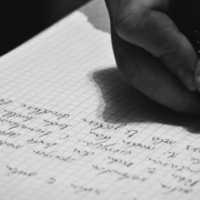 Hand holding a pen and writing on a sheet of paper