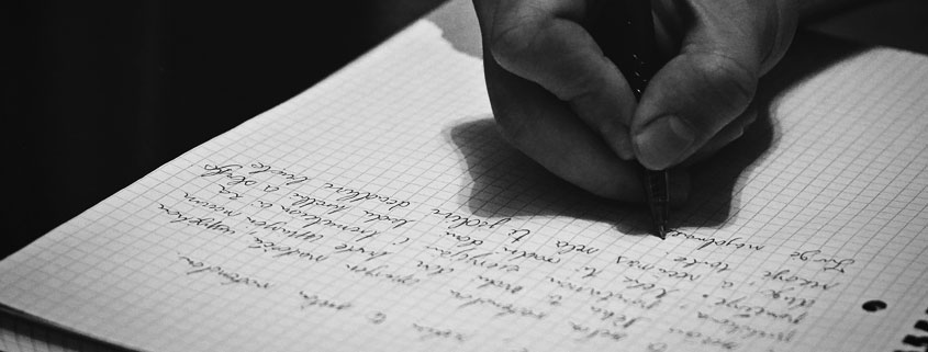 Hand-Writing-With-Pen-on-Paper Hand holding a pen and writing on a sheet of paper