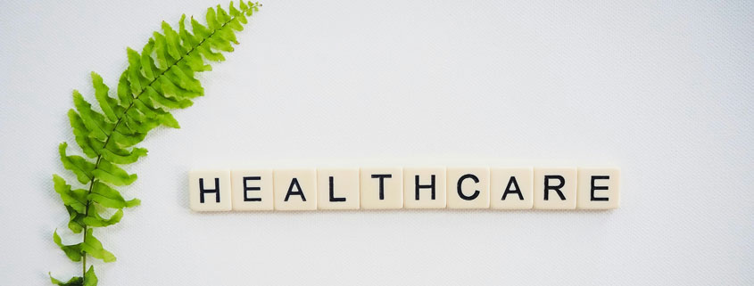 Healthcare-Sign-Beside-Arching-Green-Leafy-Branch Healthcare sign positioned beside a curved green branch with fresh leaves