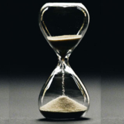 Traditional glass hourglass with sand falling from the upper chamber into the lower chamber, symbolizing the passage of time