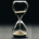 Traditional glass hourglass with sand falling from the upper chamber into the lower chamber, symbolizing the passage of time