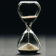 Traditional glass hourglass with sand falling from the upper chamber into the lower chamber, symbolizing the passage of time