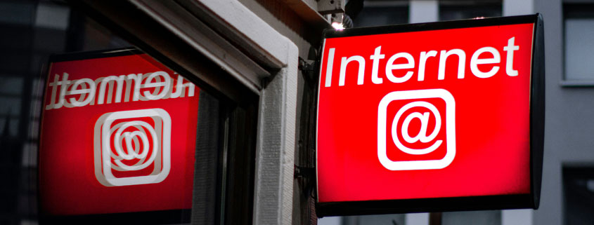Internet-Sign-Hanging-From-Side-of-Building Sign displaying the word Internet hanging from the exterior wall of a building