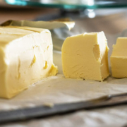Large block of golden-yellow butter with two neatly cut slices showing its smooth texture and rich color