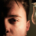 Man looking straight ahead with one side of his face illuminated by a glowing light bulb while the opposite side remains in darkness