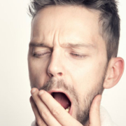Man holding his hand near his mouth while keeping his mouth open, appearing to breathe through his mouth
