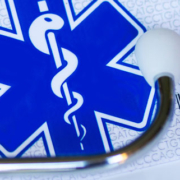 Medical stethoscope beside a Health Care card displaying a snake-entwined staff and cross symbol