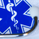 Medical stethoscope beside a Health Care card displaying a snake-entwined staff and cross symbol