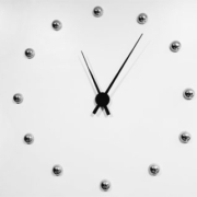 Modern analog clock featuring twelve silver spherical hour markers and contrasting black hour and minute hands