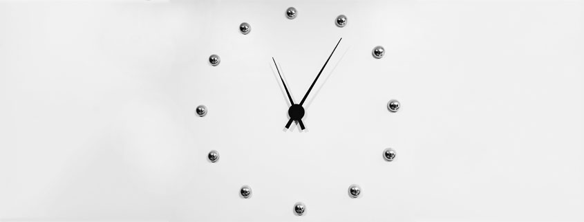 Modern analog clock featuring twelve silver spherical hour markers and contrasting black hour and minute hands