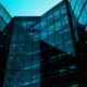 Two modern glass office buildings connected by a central architectural structure, featuring expansive glass facades and contemporary commercial design