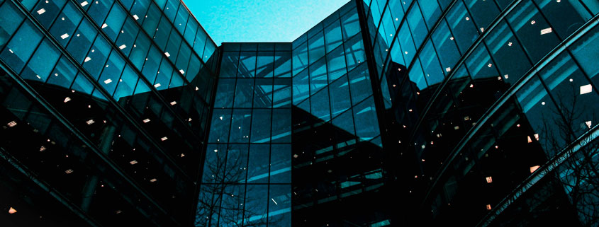 Two modern glass office buildings connected by a central architectural structure, featuring expansive glass facades and contemporary commercial design