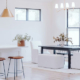 Modern open-concept home interior featuring a living room, multiple dining areas, and a kitchen with a bar counter in a connected residential layout