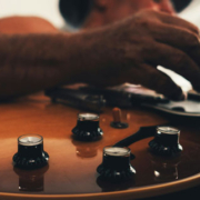 Musician playing an electric guitar connected by an audio cable, appearing focused on the instrument during a creative musical session