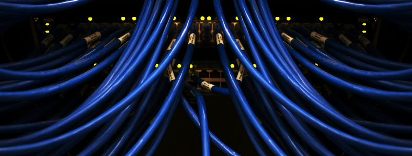 Network-Switch-Ethernet-Cables-Connected-Ports-and-LED-Lights Numerous Ethernet network cables connected to rows of network equipment ports with illuminated LED status indicators