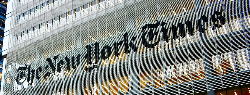 New-York-Times-Building-Illuminated-at-Night-New-York-City Exterior of The New York Times building at night, with illuminated windows and the newspaper's name visible on the facade