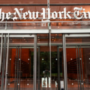 Main entrance to The New York Times building in New York City, featuring glass doors and The New York Times name displayed above the entrance
