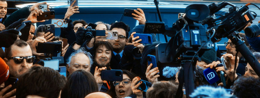 Journalists and television reporters surrounding a person on Capitol Hill with cameras and microphones during a news interview