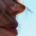 Partial view of a woman's face showing her nose and lips with loose strands of hair blowing across her skin