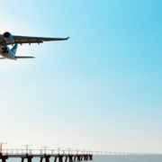 Passenger airplane descending toward a coastal airport runway while flying low over the ocean